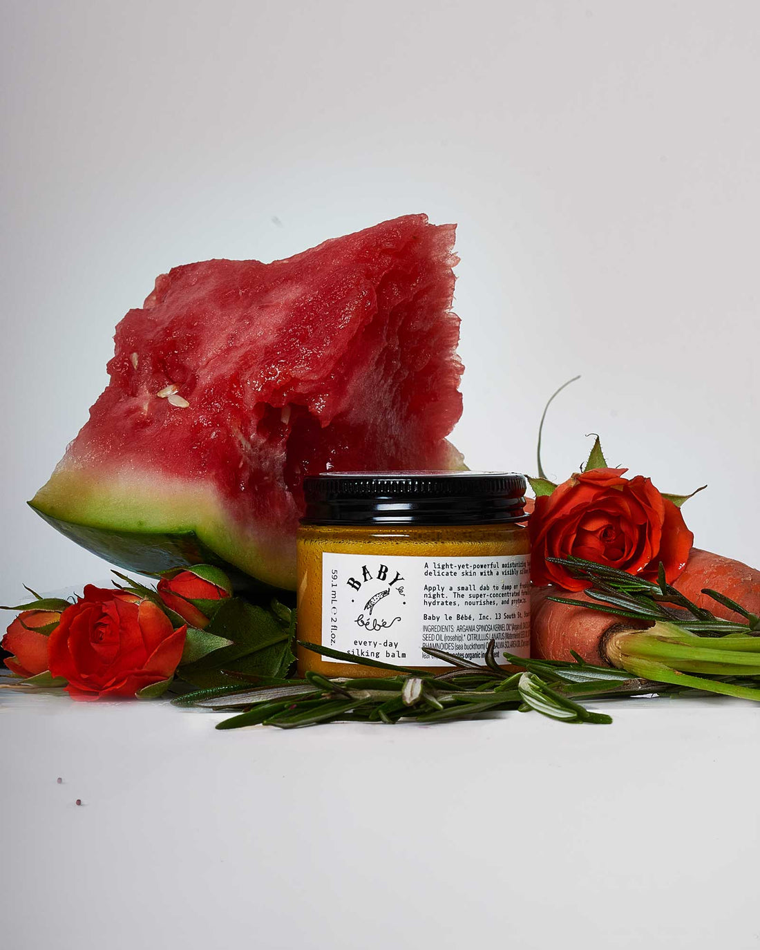 Image of a container of sinking balm surrounded by flowers and watermelon