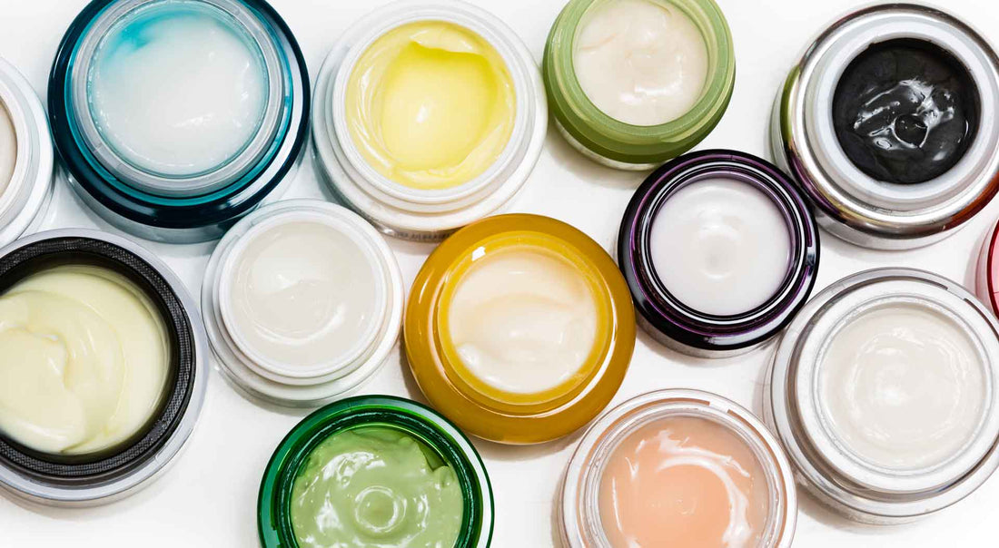 Open jars of creams and balms in assorted colors, seen from above