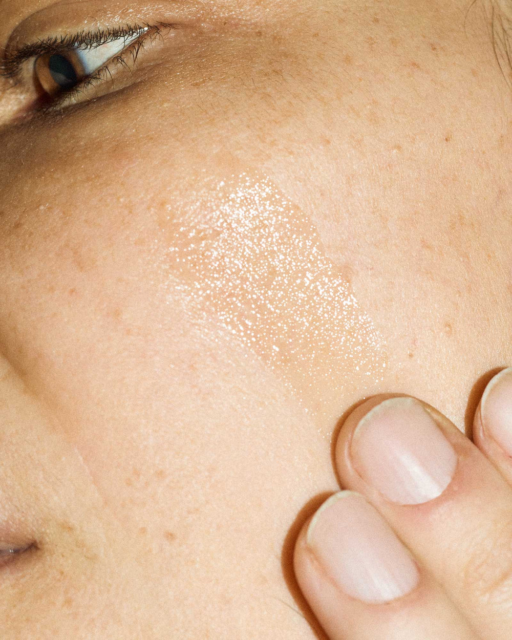 Woman applying face oil to her cheek