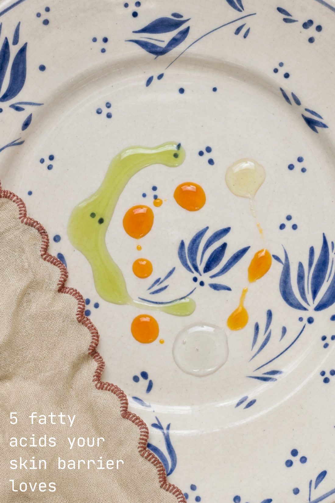 Drops of golden and green botanical oils on a blue-and-white floral plate, titled 5 fatty acids your skin barrier loves