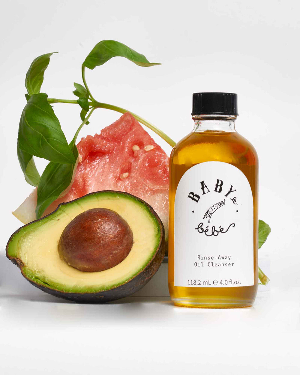 Bottle of face cleanser with an avocado and a slice of watermelon