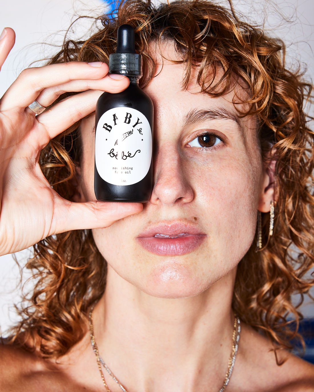 Woman holding a bottle of skin care in front of her face