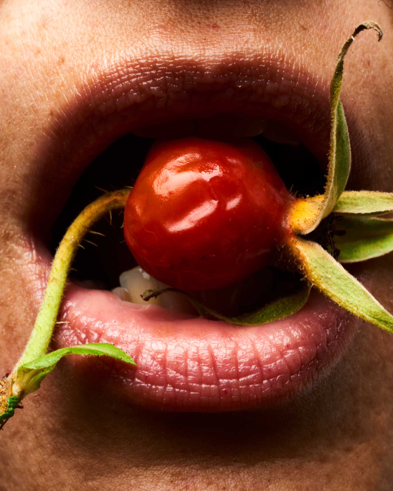 Woman holding a rosehip between her lips