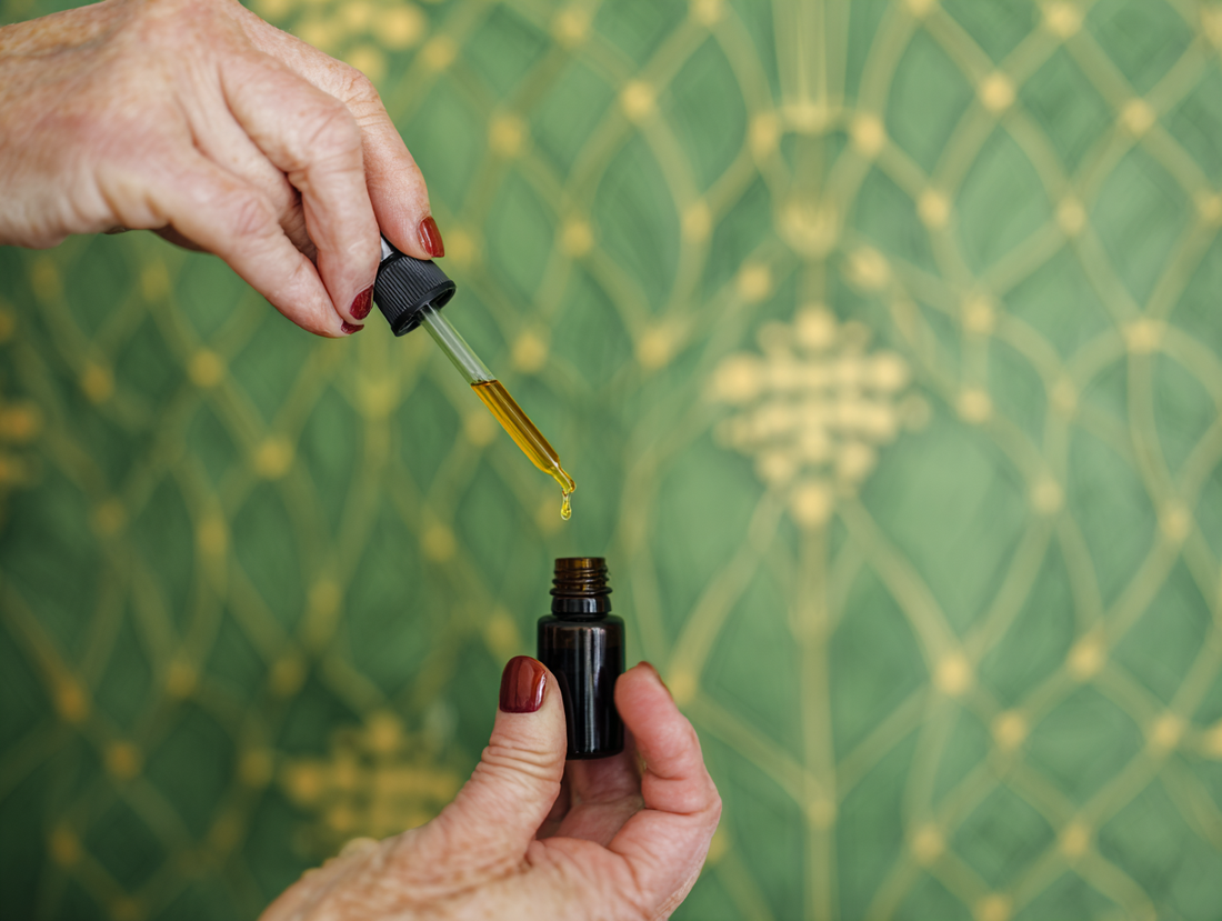 Hands holding a dropper of body oil take from the vial