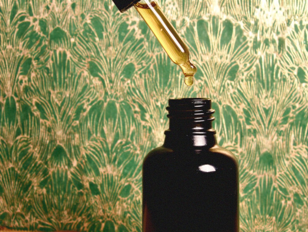 Close up view of dropper being removed from the vial of product.