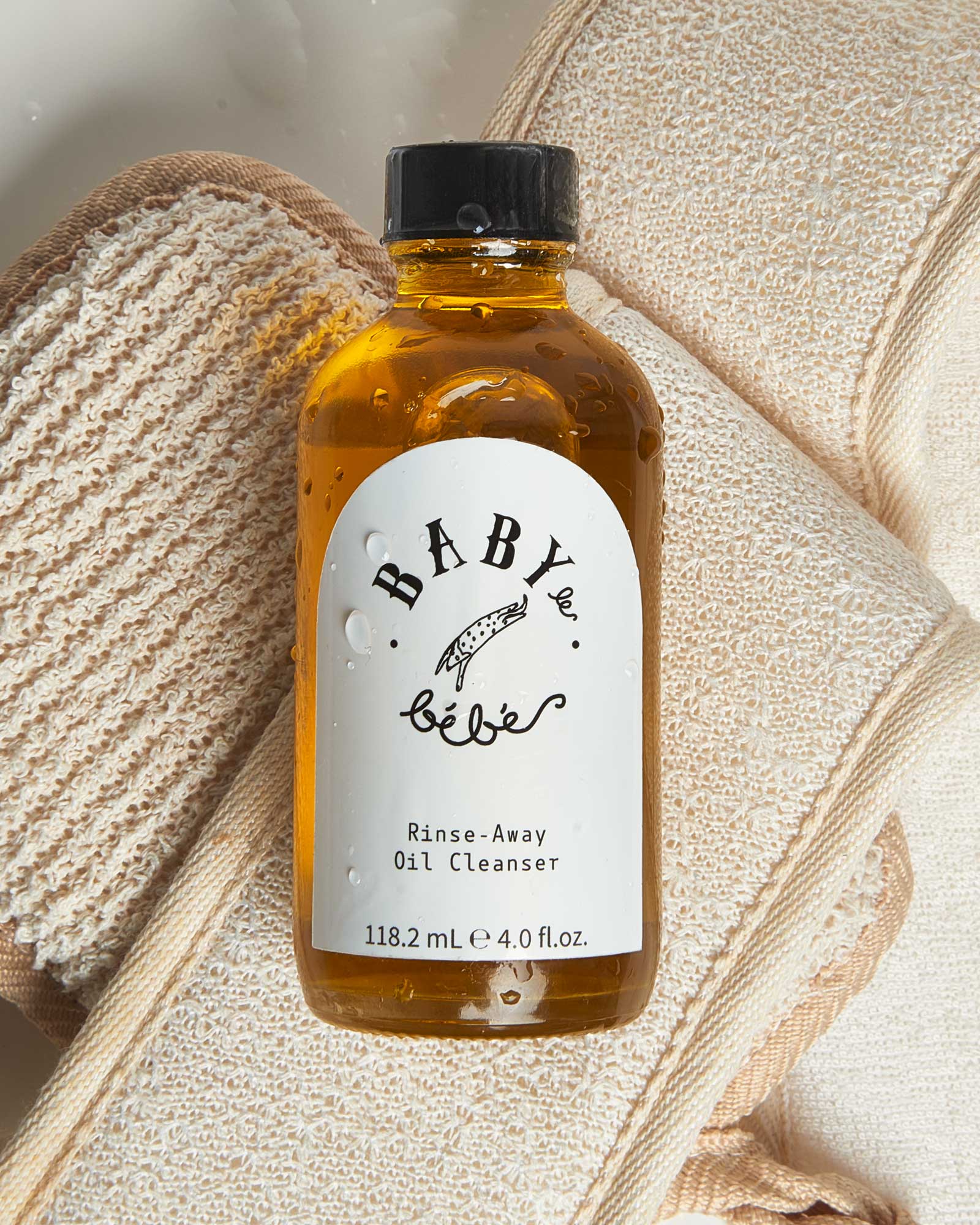 Rinse-Away Oil Cleanser bottle resting on a textured washcloth